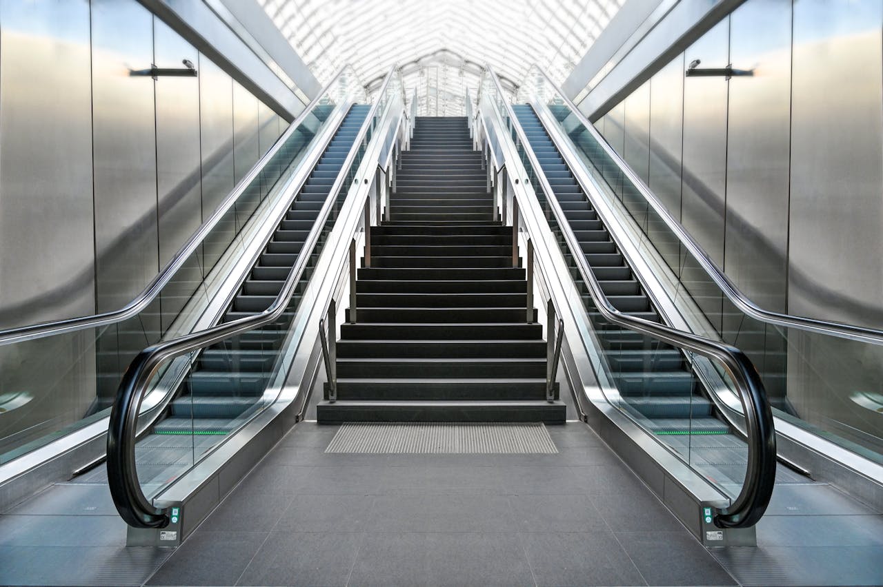 A futuristic indoor escalator and staircase with sleek, modern architecture.